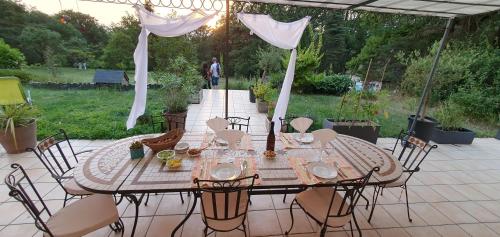 a table and chairs under an umbrella on a patio at les bois de ravel chambres d'hôtes in Ravel