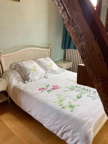 Una cama con sábanas blancas con flores. en Chambre d'Hôte du Pic Drille, en Charmont-sous-Barbuise