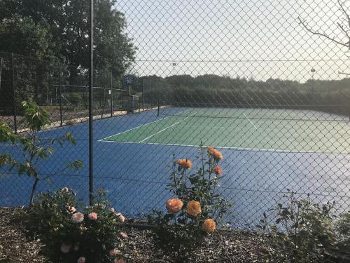 a tennis court behind a fence with a tennis court at A luxury Boutique Barn set within 2 acre grounds 