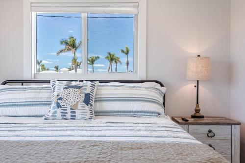 a bedroom with a bed with a window with palm trees at Good Vibes and Tan Lines! Private Beach with Heated Pool - Villa Good Times, Fort Myers Beach in Fort Myers Beach