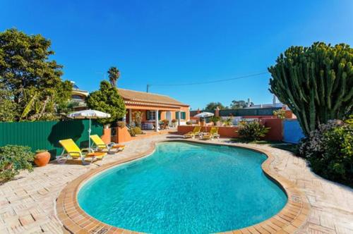 a swimming pool in a yard with chairs and a house at NEW! Poiso do Guincho by GalanteVasques in Carvoeiro