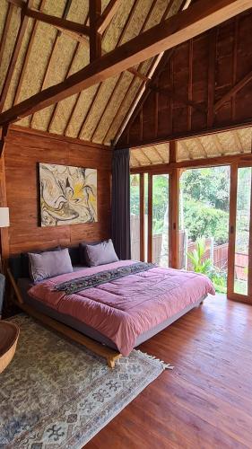 een slaapkamer met een groot bed in een houten kamer bij RUMAH KAYU MATARAJA VILLA - TABANAN in Perean