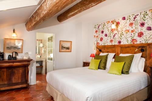 a bedroom with a large white bed with green pillows at Le Clair de la Plume - Teritoria in Grignan