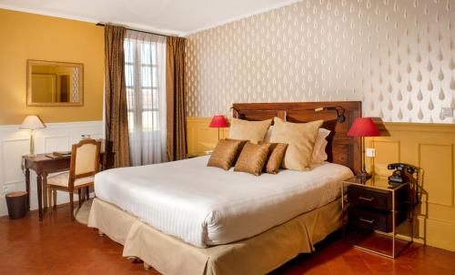 a bedroom with a large bed and a desk and a desk at Le Clair de la Plume - Teritoria in Grignan