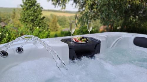 a tub with two glasses of wine and a bowl of fruit at Tó Kincse Vendégház in Kustánszeg