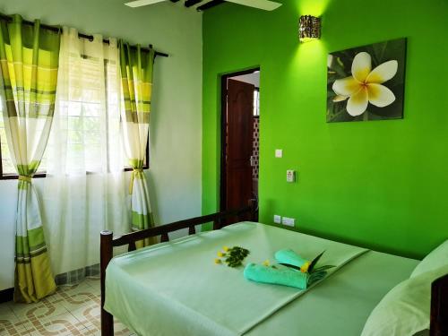 Dormitorio verde con cama con pared verde en Frangipani House Nungwi Zanzibar en Nungwi