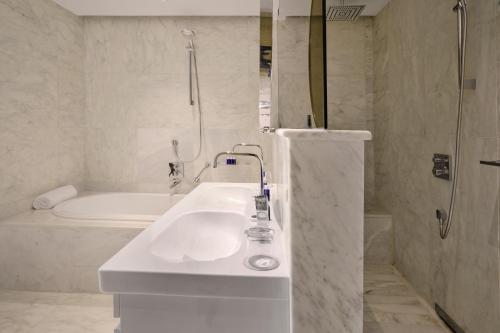 a white bathroom with a sink and a bath tub at Tunis Marriott Hotel in Tunis