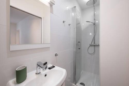 une salle de bain blanche avec un lavabo et une douche dans l'établissement 49 Rochechouart - Cozy apartment near Montmartre, à Paris