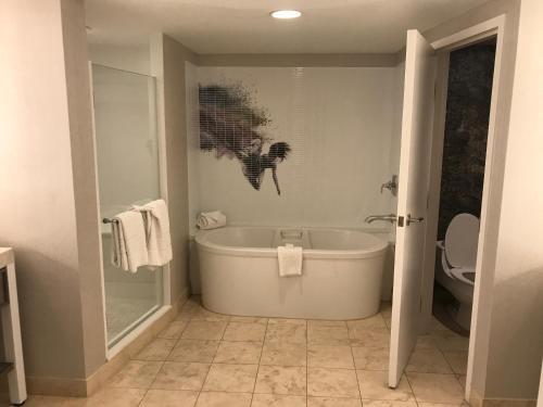 a bathroom with a bath tub and a toilet at Devine Unit by Planet Hollywood Casino Strip Las Vegas in Las Vegas