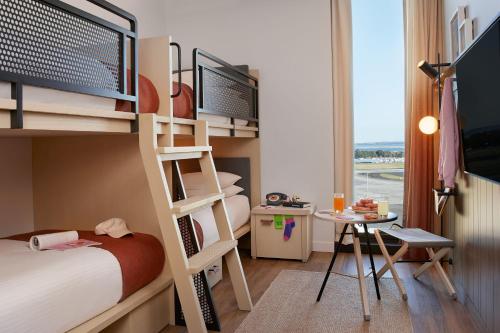 a bedroom with bunk beds with a desk and a table at Moxy Sydney Airport in Sydney