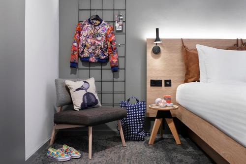 a bedroom with a bed and a chair and a coat at Moxy Manchester City in Manchester