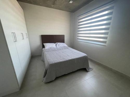 a white bedroom with a bed and a window at Dpto zona Luque, cerca del aeropuerto y centros comerciales in Luque