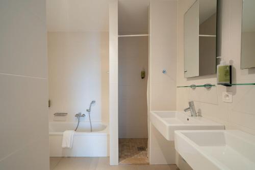 une salle de bain blanche avec deux lavabos et une douche dans l'établissement Smartflats - Central Antwerp, à Anvers