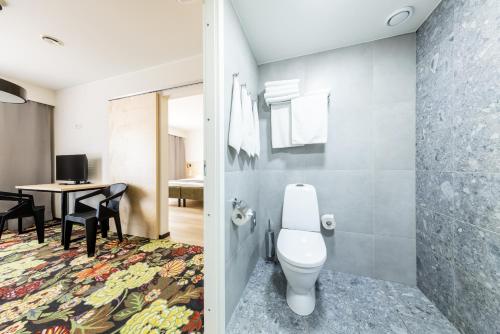 a bathroom with a toilet and a table with chairs at Saaremaa Rannahotell ' Beach Hotel in Mändjala