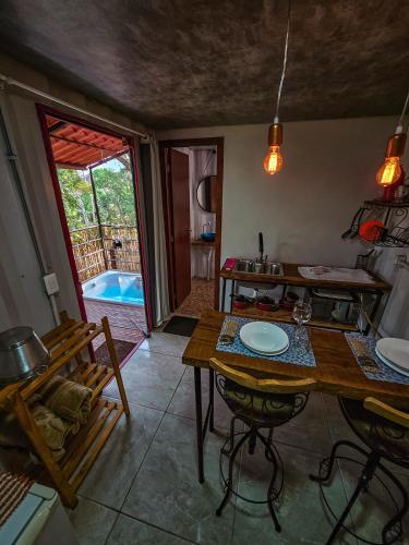 a kitchen with a table and a dining room with a view at Pousada Cipó Container Chalés Privativos com lareira - Centro da cidade in Serra do Cipo