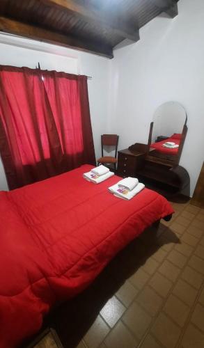ein rotes Bett mit einer roten Decke und einem Stuhl in der Unterkunft Eduardo in Malargüe
