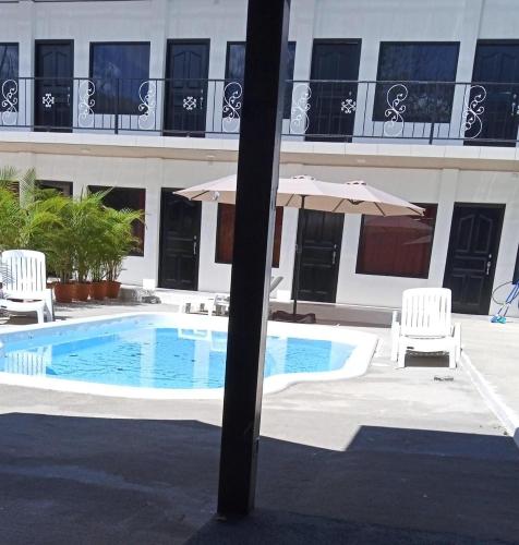 a swimming pool with two chairs and an umbrella at HOTEL Y RESTAURANTE RANCHO DE SEBAS in Nicoya