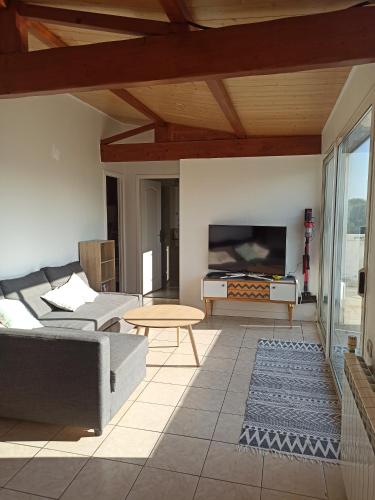 a living room with a couch and a table at Appart'cosy - 7 personnes in Saint-ouen-dʼAunis