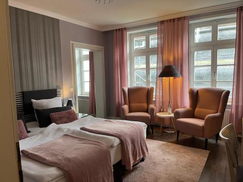 Habitación de hotel con 1 cama y 2 sillas en Rein Klassik Hotel en Bad Pyrmont