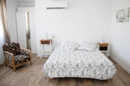 a white bedroom with a bed and a chair at Superbe appartement - L'escapade in Onzain