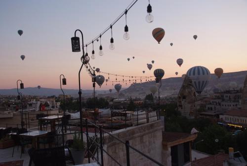 a group of hot air balloons flying over a city at Peruna Cave in Goreme