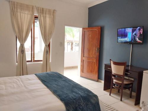 a bedroom with a bed and a desk and a television at The Coral in Pretoria