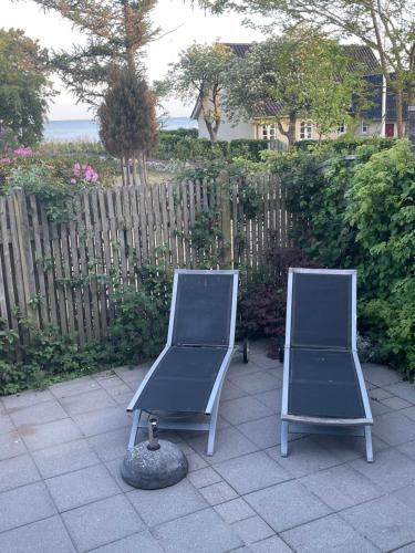 two chairs sitting on a patio next to a fence at Rørvig Bed & Kitchen in Rørvig