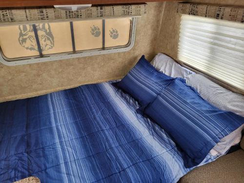 Una cama con sábanas azules y una ventana en una cabaña en Moceanset Getaways - Ocean, Mountain & Sunset Views - Cozy Accommodations en Dingwall
