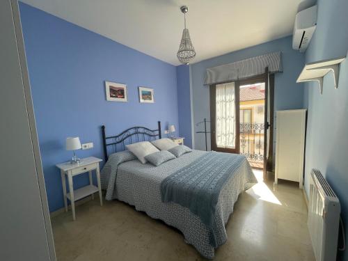 niebieska sypialnia z łóżkiem i oknem w obiekcie Apartamento Alameda del Tajo III Centro Parquing w mieście Ronda