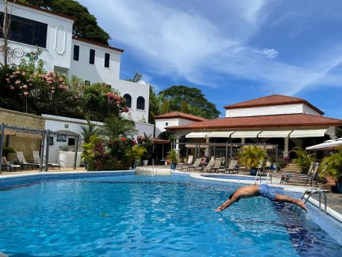 a man diving into a swimming pool at a hotel at Shana by the Beach Manuel Antonio in Manuel Antonio