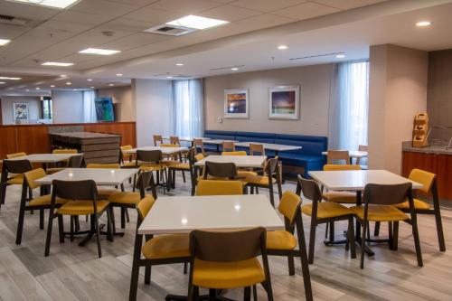 Un comedor con mesas blancas y sillas amarillas. en Fairfield Inn & Suites Anaheim North Buena Park, en Buena Park