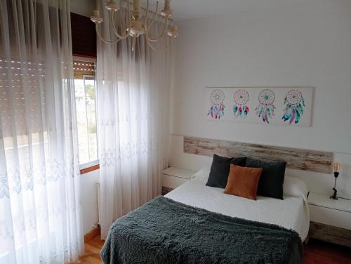 1 dormitorio con cama y lámpara de araña en Casa campo con piscina La Arboleda, en Amoeiro