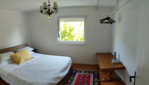 Schlafzimmer mit einem Bett, einem Fenster und einem Teppich in der Unterkunft Kuca Vujovic in Belgrad