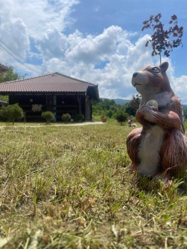 a statue of a bear sitting in the grass at Etno selo Rasinski Lug in Ravni