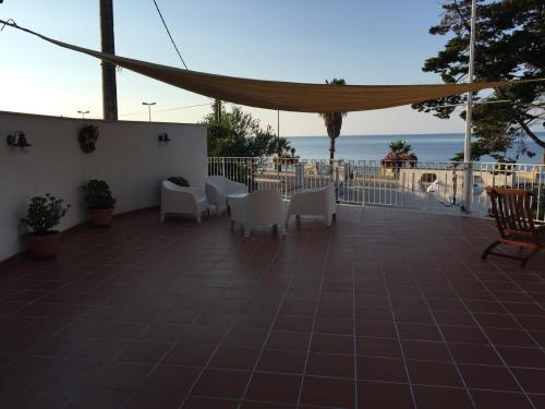 a patio with white chairs and a view of the ocean at B&B Villa sul Mare in Melito di Porto Salvo