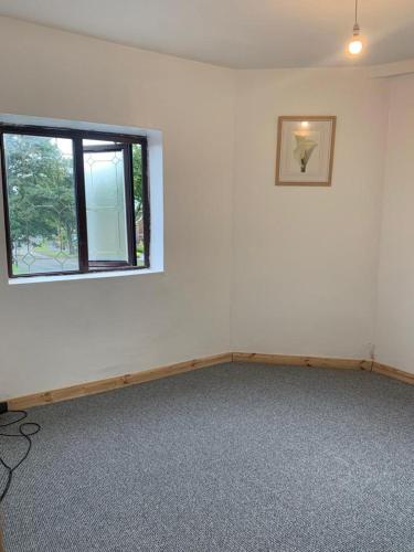 an empty room with a window and a white wall at One Lovely Apartmt 1 Double & 2 Camp Beds in Stoke on Trent