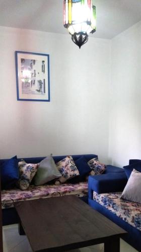 uma sala de estar com um sofá azul e uma mesa em Appartement calme au centre em Oujda