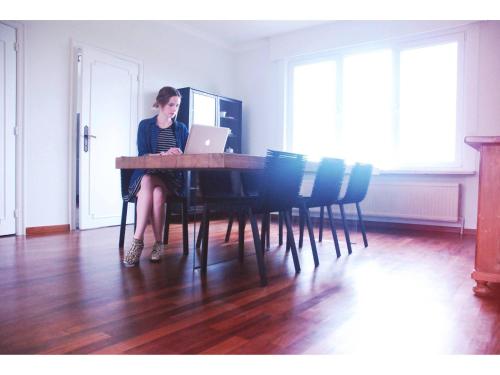a woman sitting at a table with a laptop at Holiday home Zelenachten in Zele