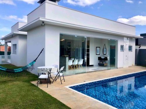 une maison blanche avec une piscine devant dans l'établissement Casa dos sonhos, relaxar Ninho Verde 1 com Piscina, à Quadra