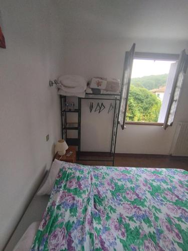a bedroom with a bed with a floral bedspread and a window at La Maison de Raph in Villeneuve dʼOlmes