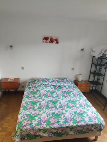 a bed in a room with a floral blanket on it at La Maison de Raph in Villeneuve dʼOlmes