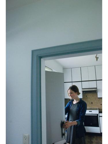 a woman standing in a kitchen looking in a mirror at Holiday home Zelenachten in Zele