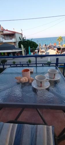 a table with two cups and plates on a table near the beach at Mana mia Seaside Apartments in Leptokaria