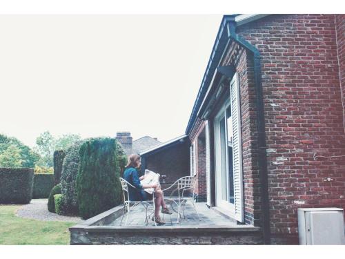 two people sitting on a porch of a brick building at Holiday home Zelenachten in Zele