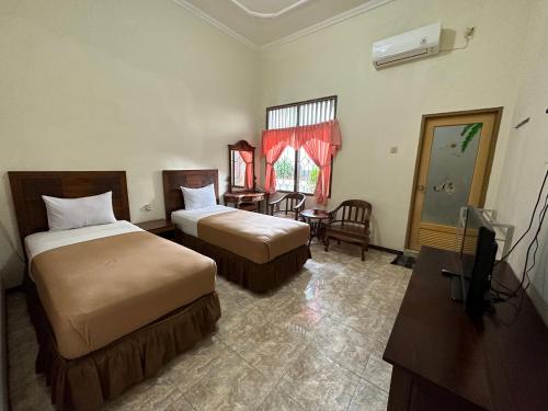 a hotel room with two beds and a table and a television at Hotel Winong Asri in Pati