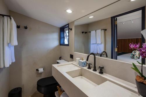 a bathroom with a sink and a large mirror at Sandi Hotel in Paraty