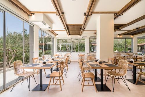 a dining room with tables and chairs and large windows at Luxury Villa Muse Calliope in Matala
