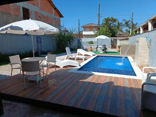 un patio con mesa, sillas y piscina en Casa OliMar fins de semana, en Bertioga