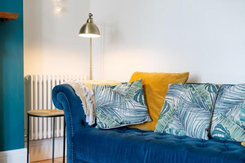 a blue couch with pillows on it in a room at Ty Calon - 3 storey 1920s home, close to beach & the city- close to theatre- perfect for family & friend breaks or longer term for contractors, crew and cast in Swansea