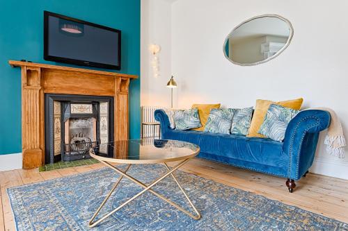 a living room with a blue couch and a fireplace at Ty Calon - 3 storey 1920s home, close to beach & the city- close to theatre- perfect for family & friend breaks or longer term for contractors, crew and cast in Swansea